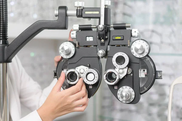 Young ophthalmologist doing visual test for customer using Bifocal Optometry eyesight measurement device in optical center, eyecare concept.