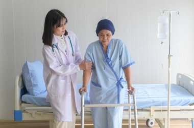 Doktor, hastanede başörtüsü takan kanser hastası bir kadına Walker 'la, sağlık hizmetleriyle ve tıbbi konseptle yardım ediyor.