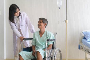 Doktor, yaşlı bir hastaya hastane, sağlık ve tıbbi konseptte tekerlekli sandalyeye taşınması için yardım ediyor.