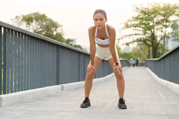 Spor giyim sektöründe genç bir kadın. Şehir parkında yorgun ve bitkin. Sağlıklı ve Yaşam Tarzı..
