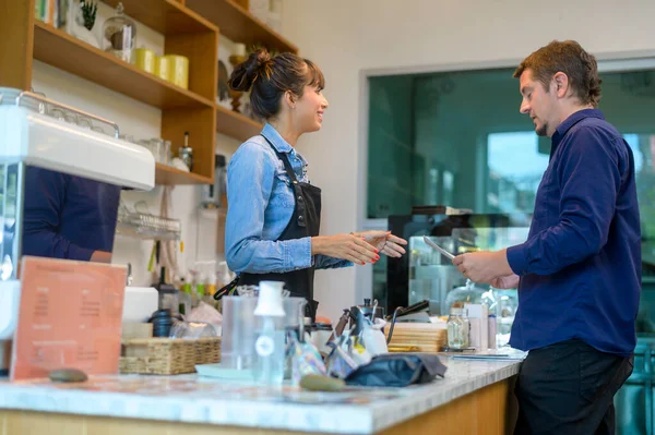 若いサービス心バリスタ女性とお客様でコーヒーショップ — ストック写真