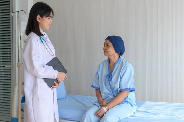 Cancer patient woman wearing head scarf after chemotherapy consulting and visiting doctor in hospital..