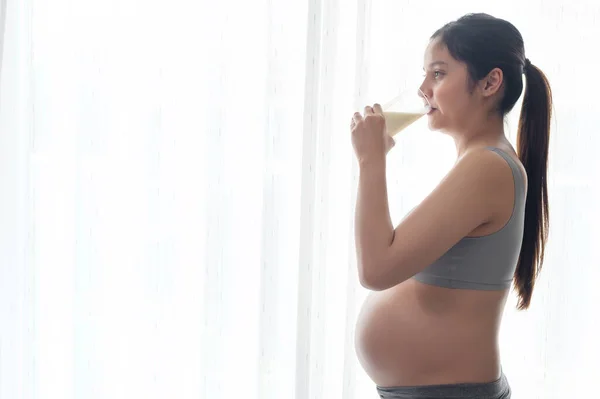 Young pregnant woman drinking milk at home, healthcare and pregnancy care