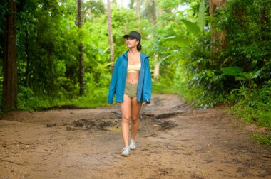 Spor kıyafetleri içinde güzel bir Asyalı kadın dağ yolunda yürüyüş, seyahat ve eko-turizm konsepti.