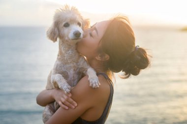 Gün batımında, yaz tatilinde, tatilde, hayat tarzı konseptinde köpeğiyle eğlenen ve rahatlatan güzel bir kadın..