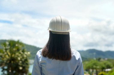 Deniz kenarında koruyucu kask takan bir kadın mühendis.