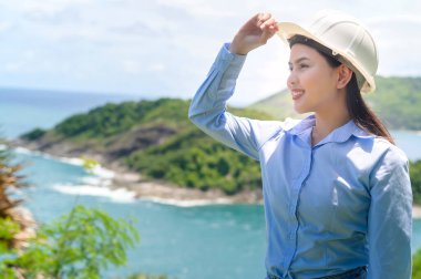 Deniz kenarında koruyucu kask takan bir kadın mühendis.