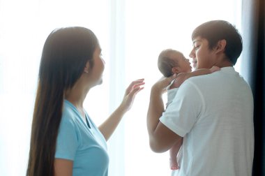 Gülümseyen genç anne ve baba yeni doğmuş bir bebek, aile ve aşk konseptiyle