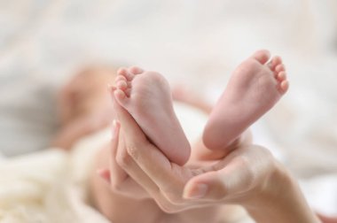 Yeni doğmuş bebeğin ayaklarını tutarken ellerim kapalı.