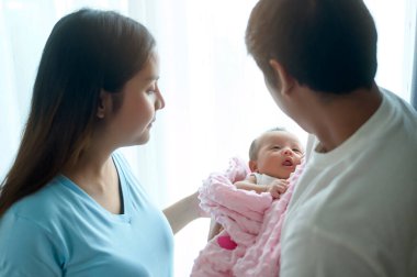 Gülümseyen genç anne ve baba yeni doğmuş bir bebek, aile ve aşk konseptiyle