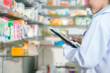 Modern bir eczanede tablet kullanan kadın eczacının portresi..