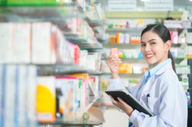 Modern bir eczanede tablet kullanan kadın eczacının portresi..