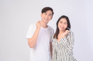 Genç gülümseyen bir adam ve elinde diş telleri olan bir kadın beyaz arka plan stüdyosu, diş sağlığı ve ortodontik konsept üzerinde....