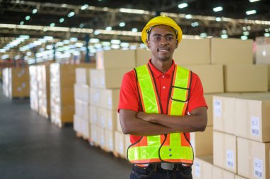 Modern deponun perakende deposunda kask takan melez genç bir erkek işçinin portresi.