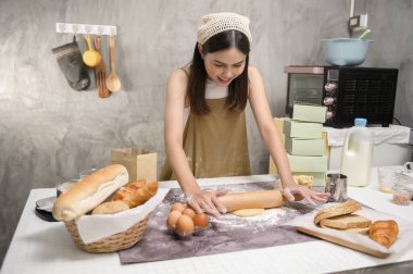 Genç ve güzel bir kadın mutfağında, fırınında ve kahve dükkanında yemek pişiriyor.