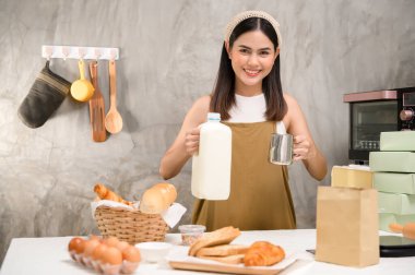Genç ve güzel bir kadın mutfağında, fırınında ve kahve dükkanında yemek pişiriyor.