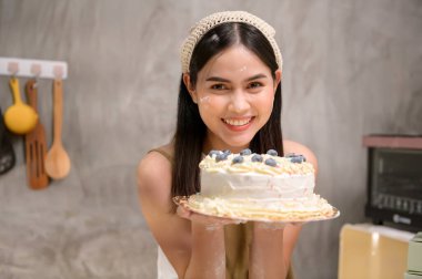 Genç ve güzel bir kadın mutfağında, fırınında ve kahve dükkanında yemek pişiriyor.