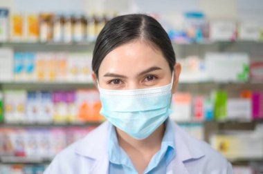 Modern bir eczanede yüz maskesi takan kadın eczacının portresi..