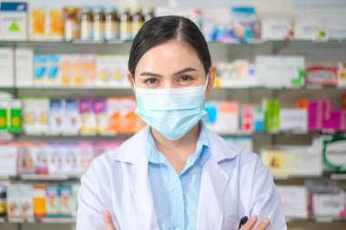 Modern bir eczanede yüz maskesi takan kadın eczacının portresi..