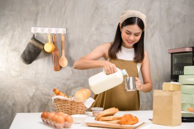 Genç ve güzel bir kadın mutfağında, fırınında ve kahve dükkanında yemek pişiriyor.