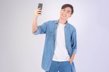 A Young asian man using smartphone over white background, technology concept. 		