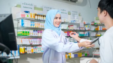 A Female muslim pharmacist counseling customer about drugs usage in a modern pharmacy drugstore.