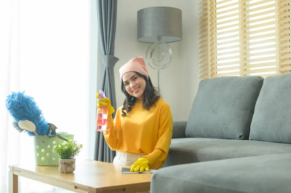 Young Happy Woman Wearing Yellow Gloves Dusting Table Living Room — Stock fotografie