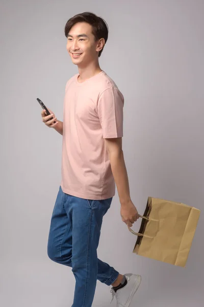 Young Asian Man Holding Smartphone Shopping Bag White Background Studio — Zdjęcie stockowe