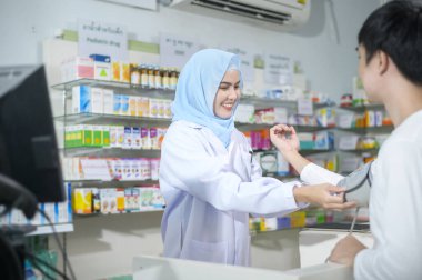 A Female muslim pharmacist counseling customer about drugs usage in a modern pharmacy drugstore.