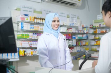 A Female muslim pharmacist counseling customer about drugs usage in a modern pharmacy drugstore.