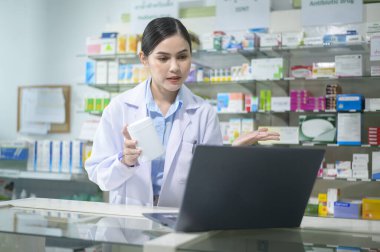 A Female pharmacist counseling customer via video call in a modern pharmacy drugstore.