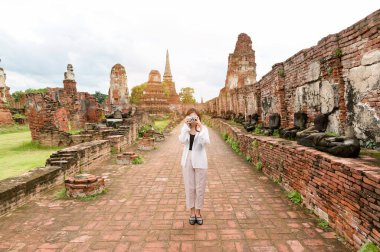 young beautiful woman traveling and taking photo at thai historical Park, Holidays and cultural tourism concept.