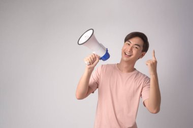 A young smiling man holding megaphone over white background studio.	