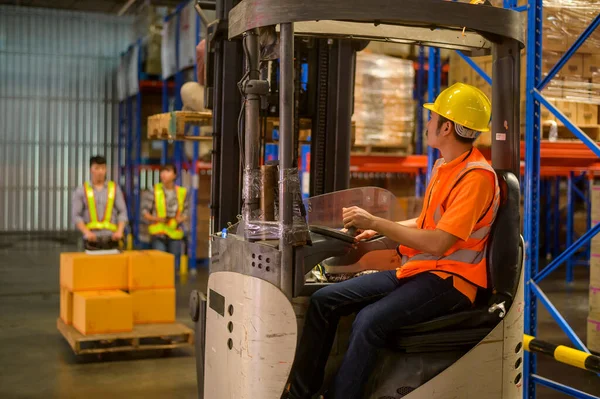 Forklift loader working between shelves full of packed boxes in warehouse, machinery and Logistics concept. 