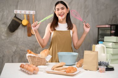 Genç ve güzel bir kadın mutfağında, fırınında ve kahve dükkanında yemek pişiriyor.