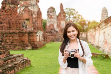 young beautiful woman traveling and taking photo at thai historical Park, Holidays and cultural tourism concept.