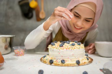 A Young beautiful muslim woman is baking in her kitchen , bakery and coffee shop business
