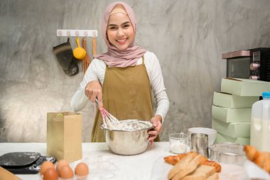 A Young beautiful muslim woman is baking in her kitchen , bakery and coffee shop business