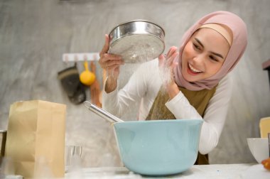 A Young beautiful muslim woman is baking in her kitchen , bakery and coffee shop business