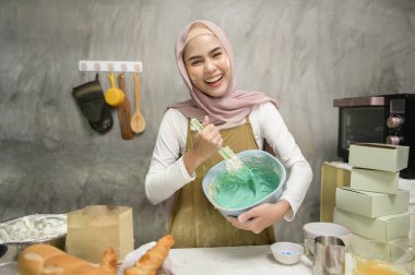 Young beautiful muslim woman is baking in her kitchen , bakery and coffee shop business