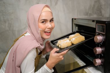 Young beautiful muslim woman is baking in her kitchen , bakery and coffee shop business