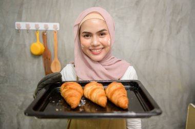 Young beautiful muslim woman is baking in her kitchen , bakery and coffee shop business