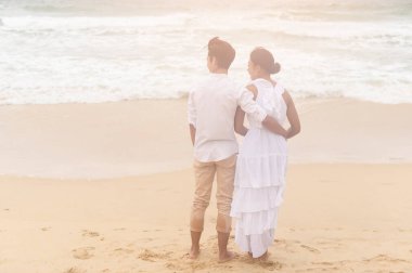 A Happy young couple wearing white dress on the beach on holidays, travel, romantic, wedding concept