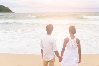A Happy young couple wearing white dress on the beach on holidays, travel, romantic, wedding concept
