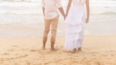 A Happy young couple wearing white dress on the beach on holidays, travel, romantic, wedding concept