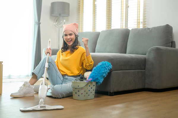A Young happy woman mopping and vacuum the floor in living room.
