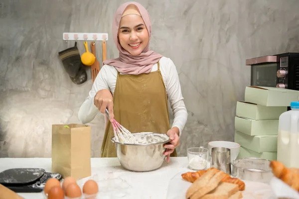 A Young beautiful muslim woman is baking in her kitchen , bakery and coffee shop business