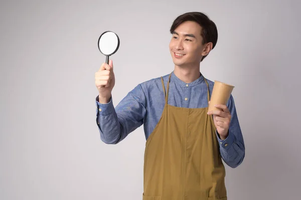 Portrait Young Asian Man Wearing Apron Holding Magnifying Glass Paper — Stock Photo, Image