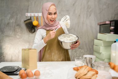 A Young beautiful muslim woman is baking in her kitchen , bakery and coffee shop business
