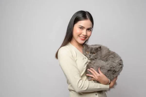 A young woman is holding lovely cat , playing with cat in studio on white background